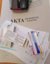 zdjęcie leków i pieczątki położonych na okładce akt śledztwa/dochodzenia