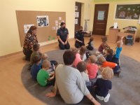 policjantki w klasie przedszkolnej prowadzą rozmowę z dziećmi, wszyscy siedzą na podłodze