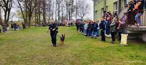 Policjantka z psem służbowym idzie wzdłuż obserwujących osób