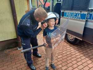 Policjant zakłada dziecku hełm na głowę
