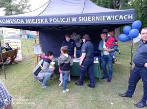 Namiot  z napisem Komenda Miejska Policji w Skierniewicach, stolik i policjanci