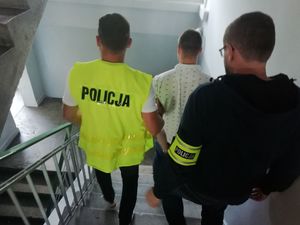 Dwóch policjantów i mężczyzna schodzą po schodach