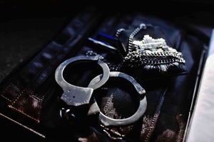 Odznaka policyjna i kajdanki położone na aktówce