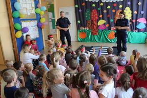 policjanci prowadzą spotkanie z przedszkolakami, dzieci siedzą na podłodze i słuchają wystąpienia