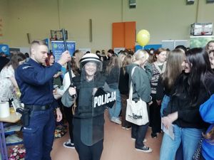 Policjanci i uczestnicy targów na hali sportowej.
