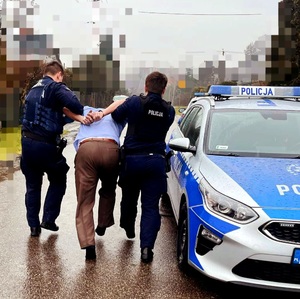 Policjanci doprowadzający zatrzymanego do radiowzu.