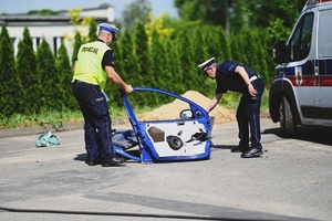 Policjanci zabezpieczający fragmenty auta, które następnie zostaną poddane oględzinom.