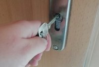 klucz trzymany w rekach ,włożony w zamek do drzwi