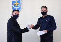 Komendant policji i prezydent miasta stoją obok siebie i podają sobie dłoń