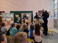 Dwie policjantki i strażak w sali przedszkolnej oraz dzieci