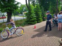 Policjant w mundurze i dziecko jadące na rowerem między przeszkodami