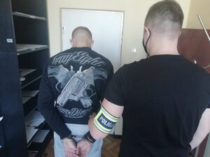 Mężczyzna z kajdankami z tyłu i policjant