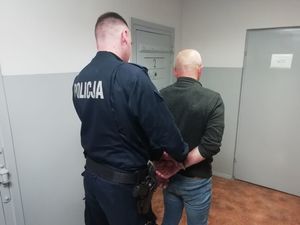 Policjant zakładający kajdanki mężczyźnie w areszcie policyjnym
