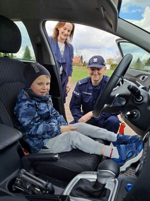 Dziecko za kierownicą samochodu obok policjant