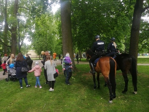 Grupa dzieci i policjanci na koniach służbowych