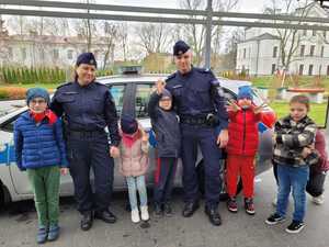 Policjanci i dzieci przy radiowozie.