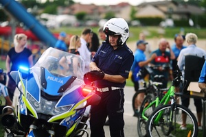 policjant ruchu drogowego przy motocyklu, w tle rowerzyści.