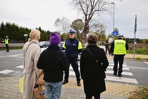 Policjant kierujący ruchem na ulicy obok piesi.