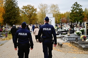 Dwóch policjantów podczas patrolu pieszego na cmentarzu.