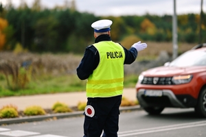 Policjant na ulicy w kamizelce odblaskowej kierujący ruchem.