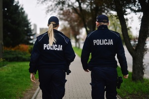 Dwóch policjantów w mundurze idzie chodnikiem
