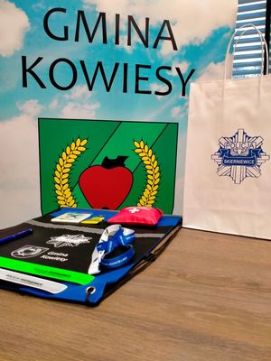 Gadżety promocyjne z logo policji i Urzędu Gminy Kowiesy na stole
