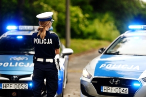 Policjantka ruchu drogowego na tle radiowozów.