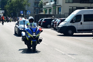 Policjant na motorze jadący na czele rajdu rowerowego.