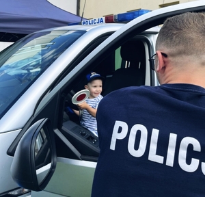 Policjant pokazujący dzieciom radiowóz.