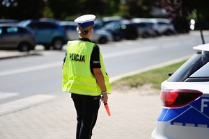 Policjanta ruchu drogowego stojąca tyłem przy radiowozie.