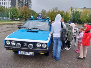 Zabytkowy policyjny radiowóz a wokół uczniowie