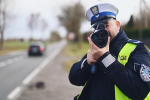 Policjant ruchu drogowego w trakcie mierzenia prędości.