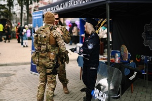 Policjantka rozmawiająca z żołnierzami na stanowisku policyjnym.