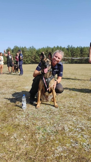 Policjantka z psem służbowym, który ma na sobie medal z zawodów.