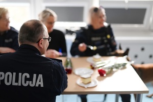 Policjant siedzący tyłem rozmawiający z policjantkami.