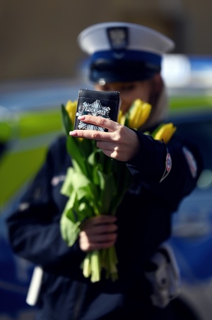 Policjantka trzymająca kwiaty oraz legitymację służbową.