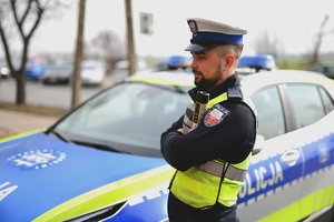 Policjant ruchu drogowego obok radiowozu.