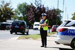Policjantka ruchu drogowego przy radiowozie.