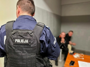 Policjant odwrócony tyłem, a w tle zatrzymany sprawca.
