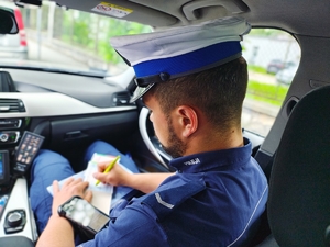 Policjant ruchu drogowego wypisujący mandant karny.