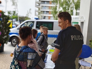 Policjant wraz z dziećmi przy olicyjnym stoisku.