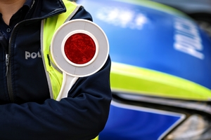Tarcza do zatrzymywania pojazdów trzymana przez policjanta.