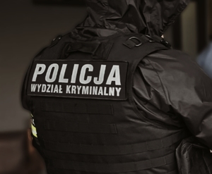 Policjant kryminalny stojący tyłem.