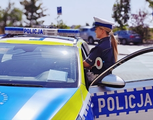 Policjantka stojąca przy radiowozie.