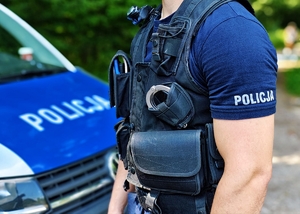 Policjant na tle radiowozu.