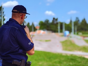 Policjant stojący tyłem, nadający komunikat przez radiostację.
