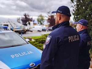 Policjanci na tle radiowozów.