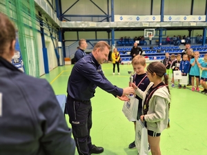 Komendant Miejski Policji w Skierniewicach wręczający uczniom puchar.