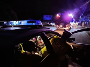 Radiowóz policyjny a w tle zdarzenie drogowe.