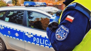 Policjant a w tle radiowóz.